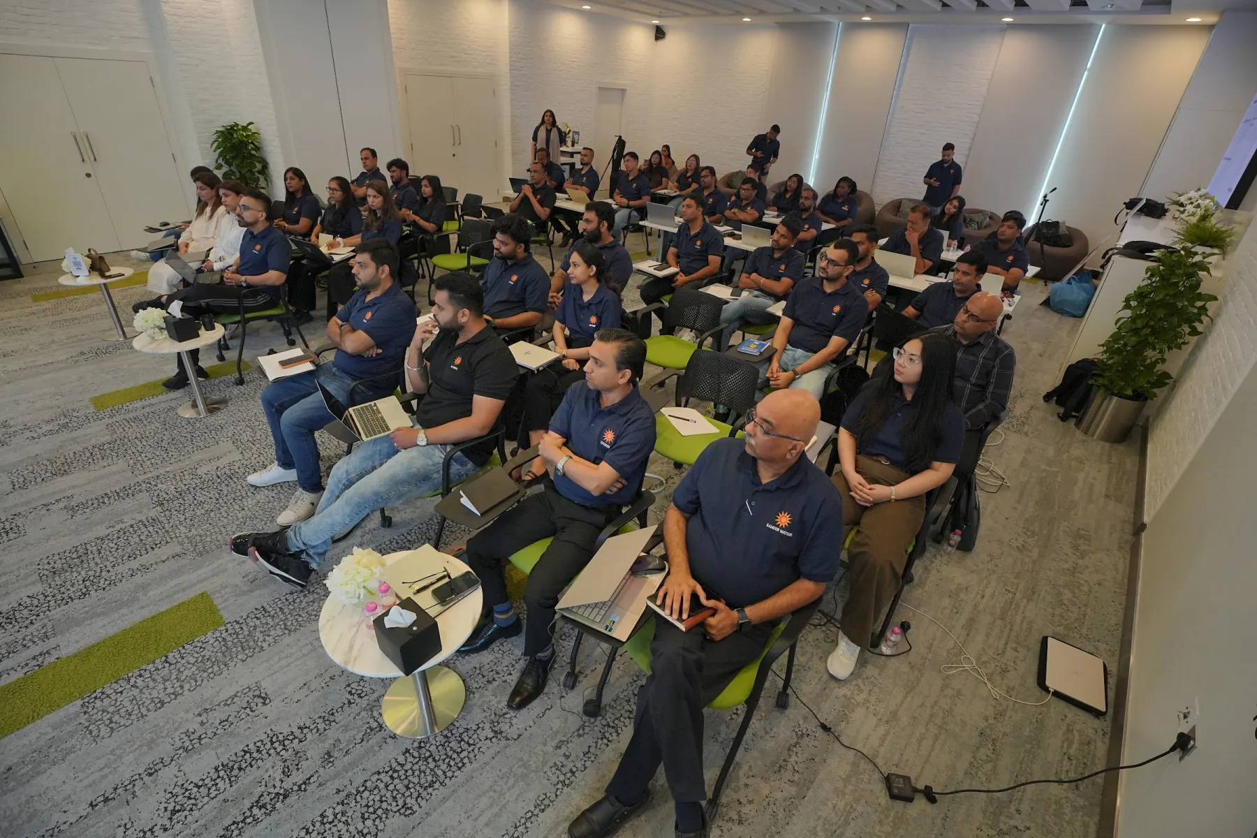 A full conference room of managers working on laptops during an Optomize corporate AI workshop