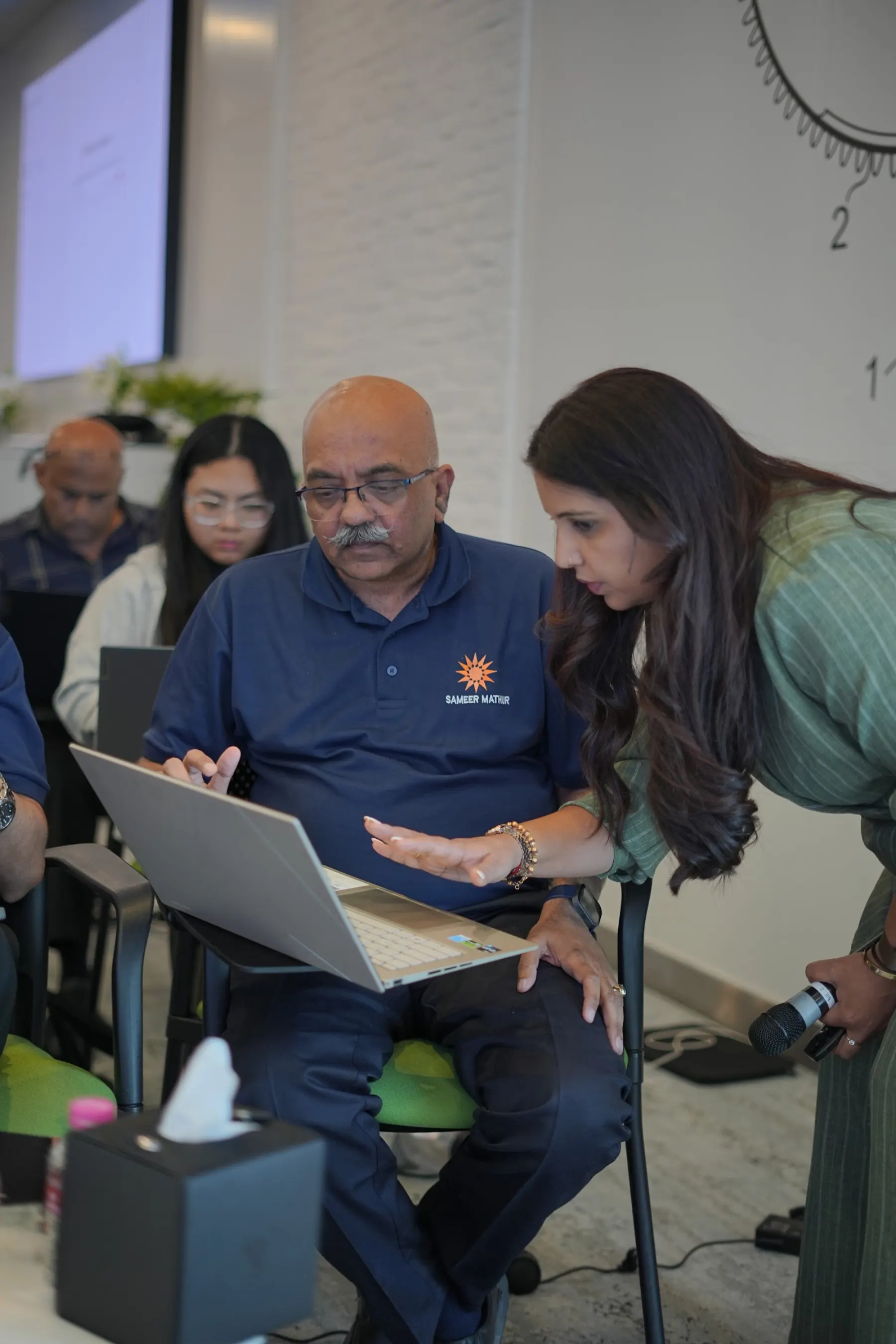 A facilitator working one-to-one with a senior manager on his laptop